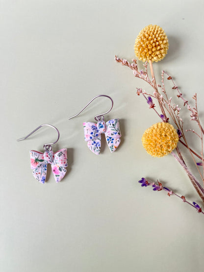 Floral earrings with a decorative yellow pom-pom on a light gray background